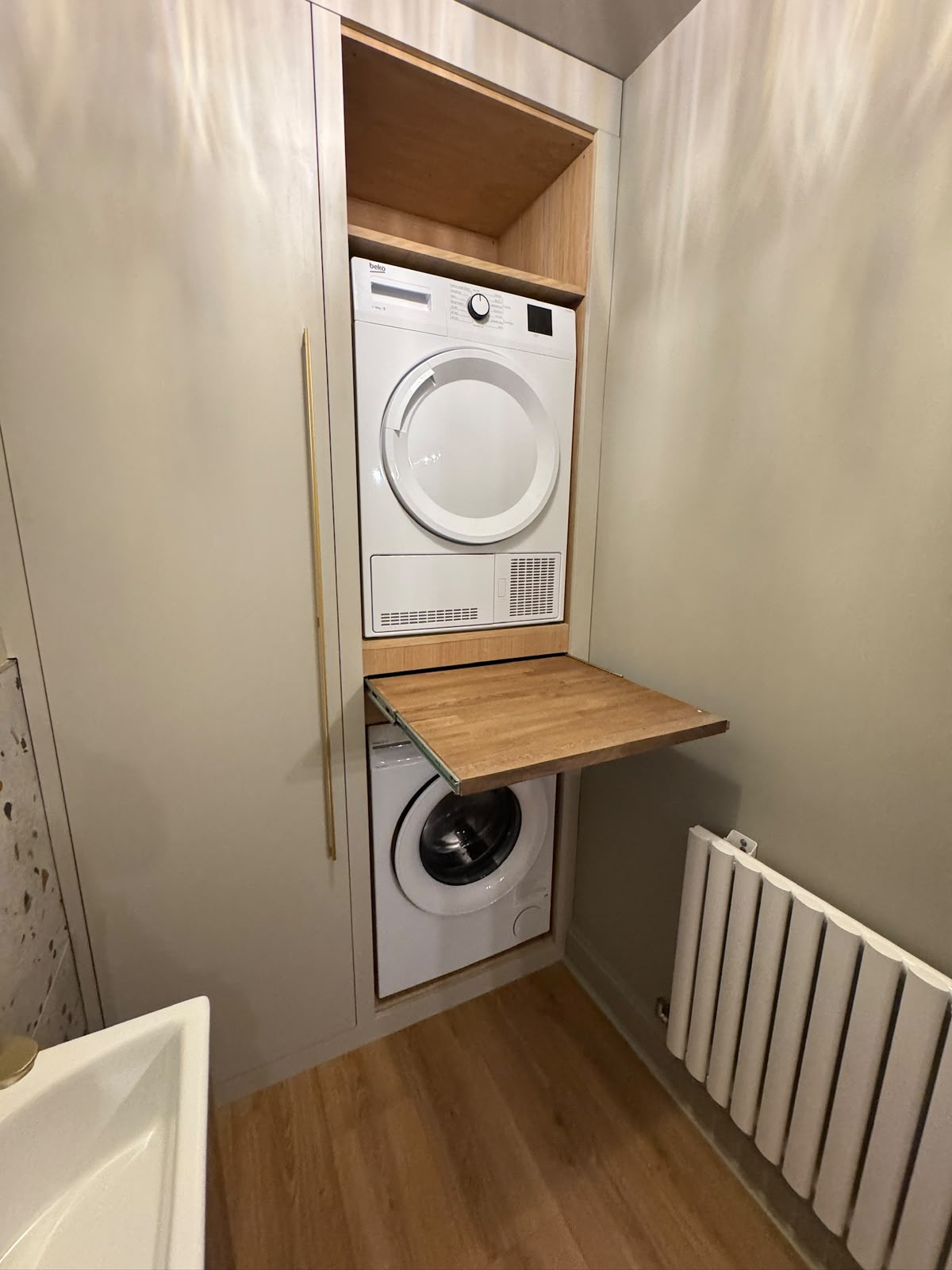 Bespoke cabinetry housing the washing machine and tumble dryer, with pull-out shelf