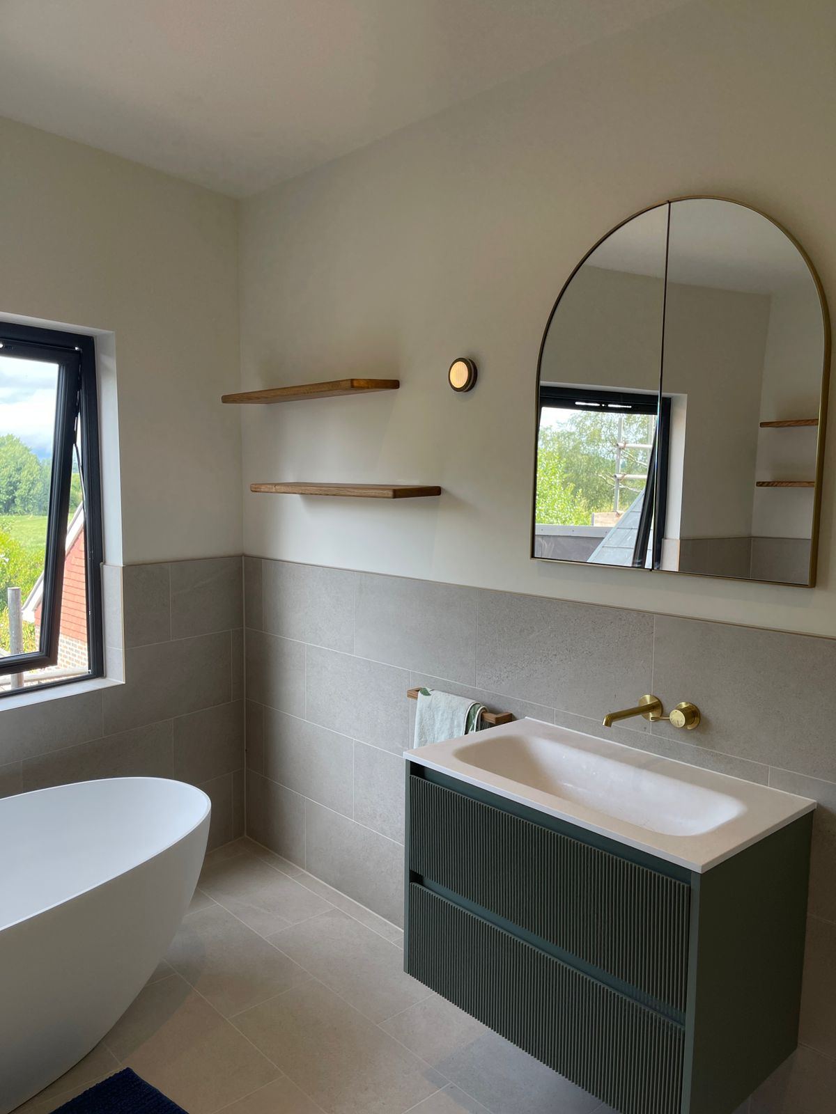 Freestanding bath, arched mirror and sage vanity with oak shelves