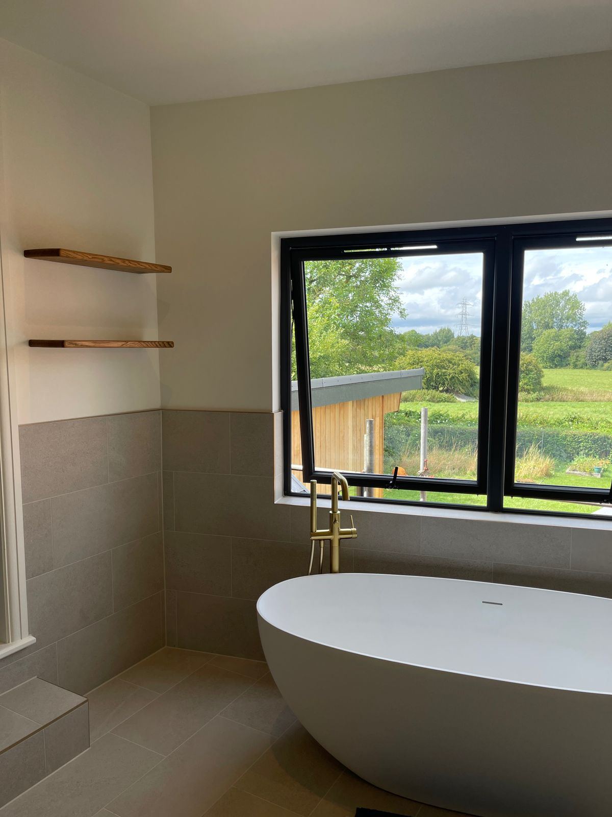 Freestanding bath beneath a picture window with countryside views