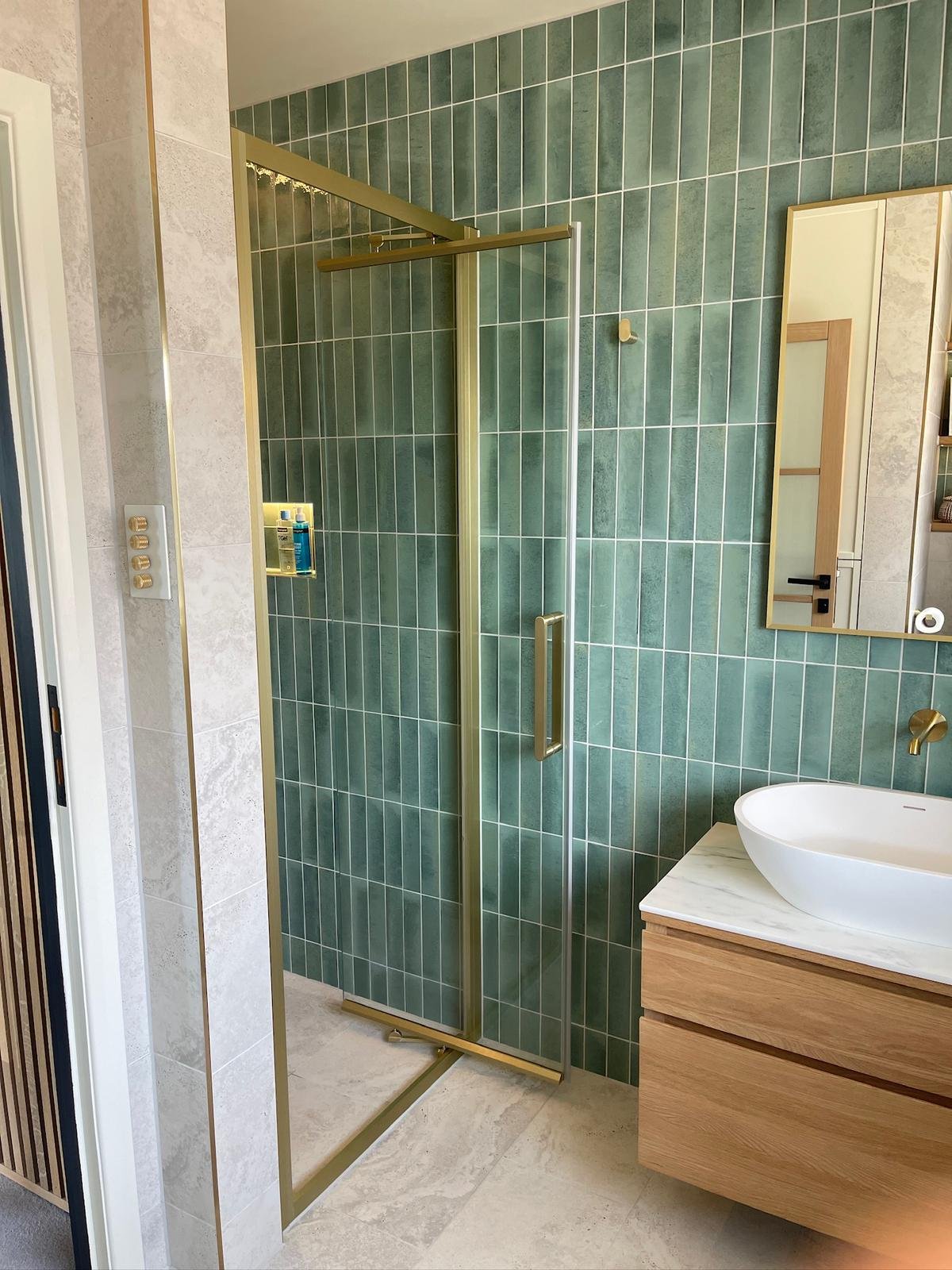 Walk-in wet deck shower with brass-framed screen beside the vanity