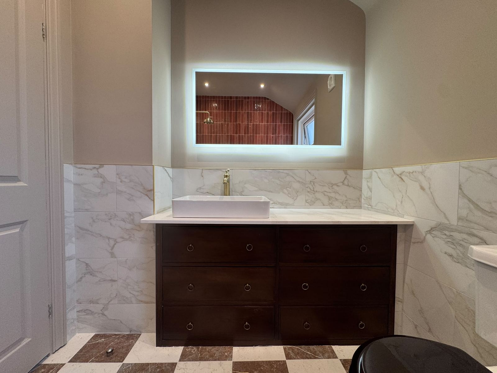 Bespoke dark cabinetry with countertop basin and illuminated mirror