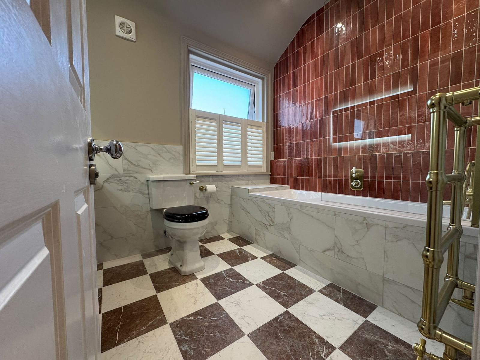 Queen Street bathroom with burgundy feature tiles, chequerboard floor and brass fittings