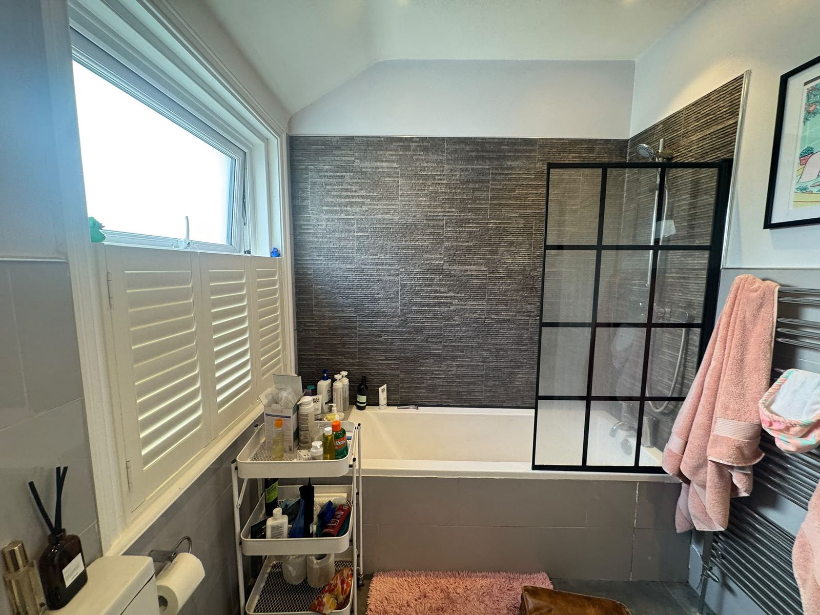Before: grey bathroom with dark feature wall and over-bath shower