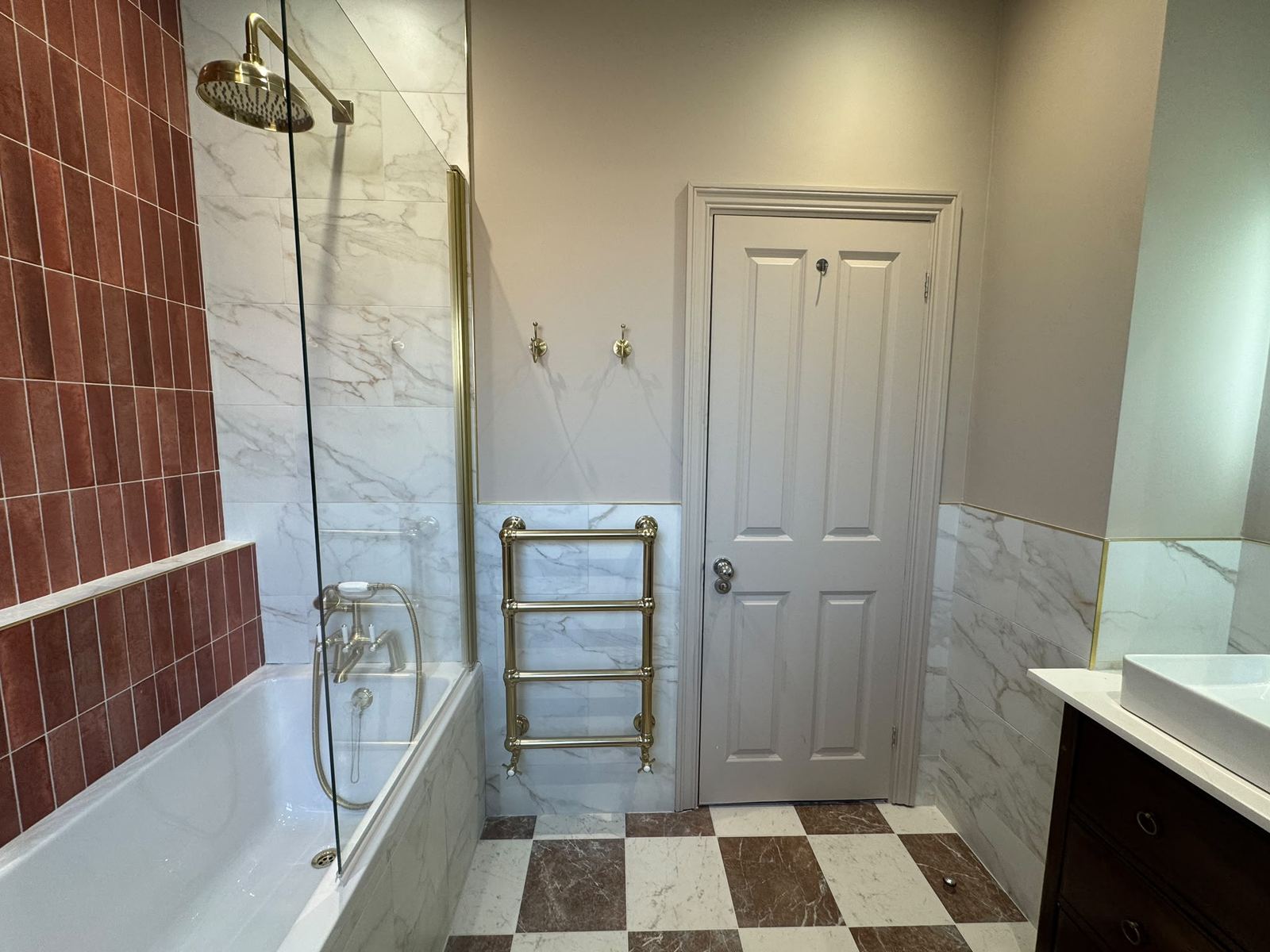Bath with marble-effect wall tiles and burgundy feature wall