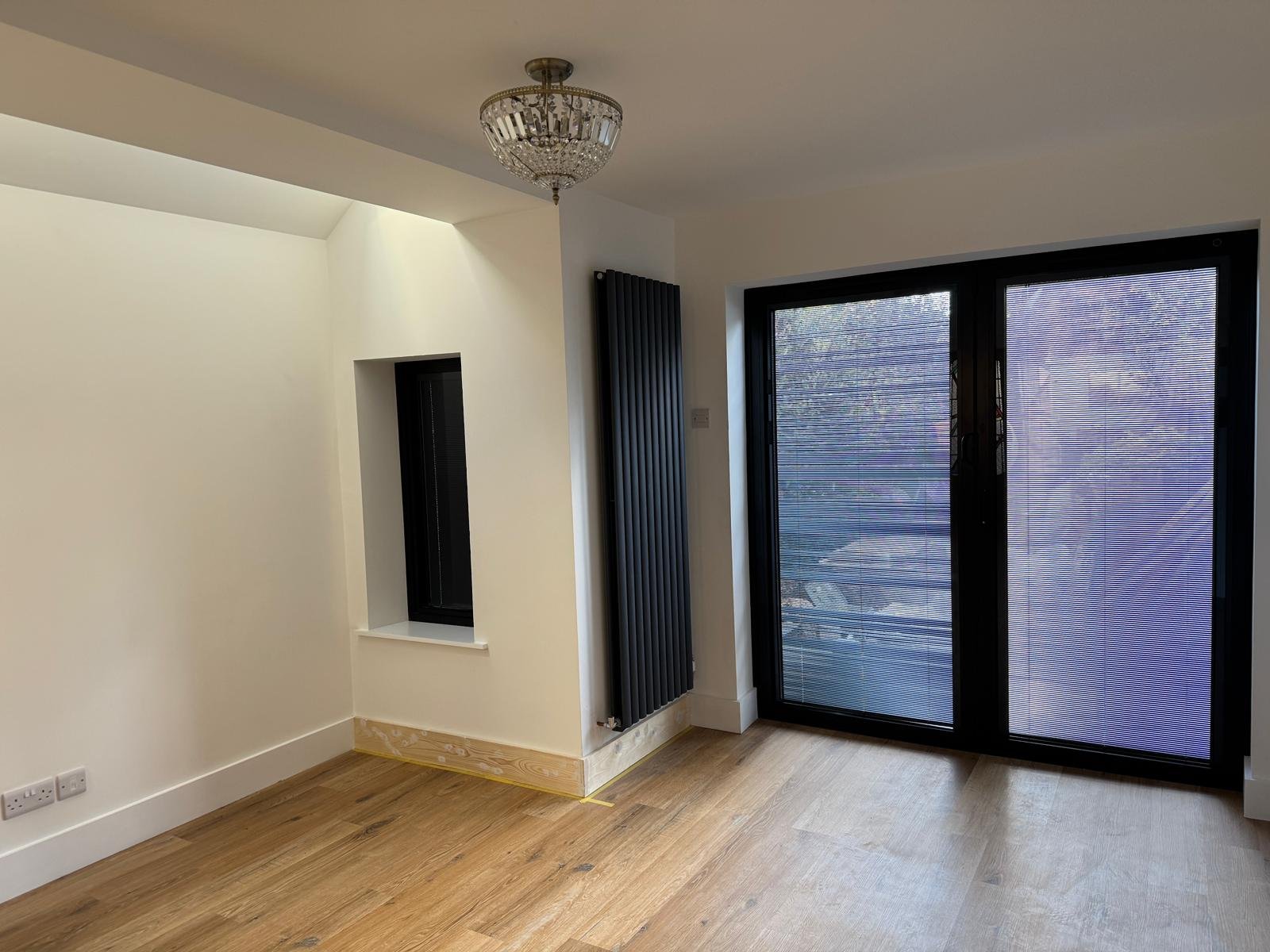 Living area with vertical radiator and patio doors onto the garden