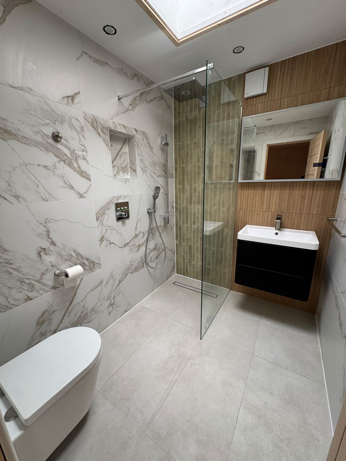 Compact bathroom with marble-look walls, olive tiled shower column and skylight