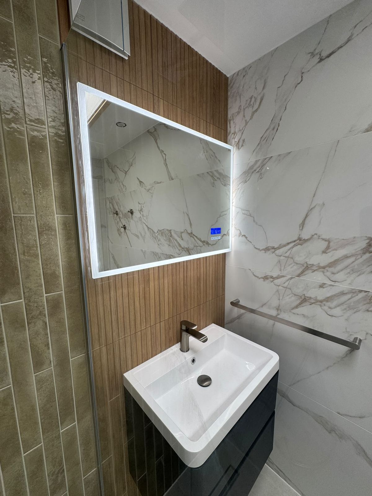 Backlit mirror over basin with olive tile column