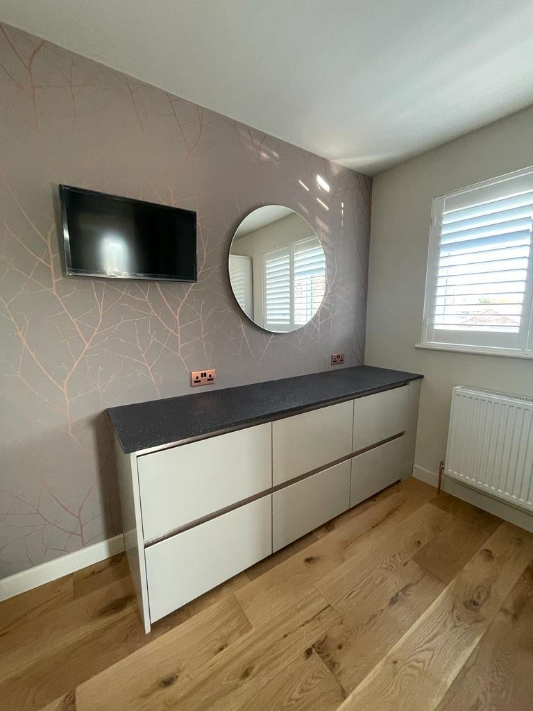 Drawers and round mirror beside the shuttered window