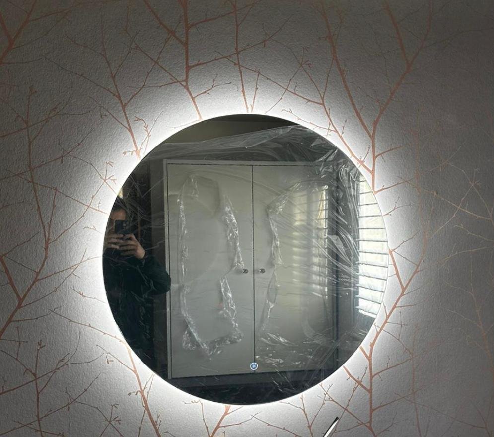 Backlit round mirror on the patterned wallpaper
