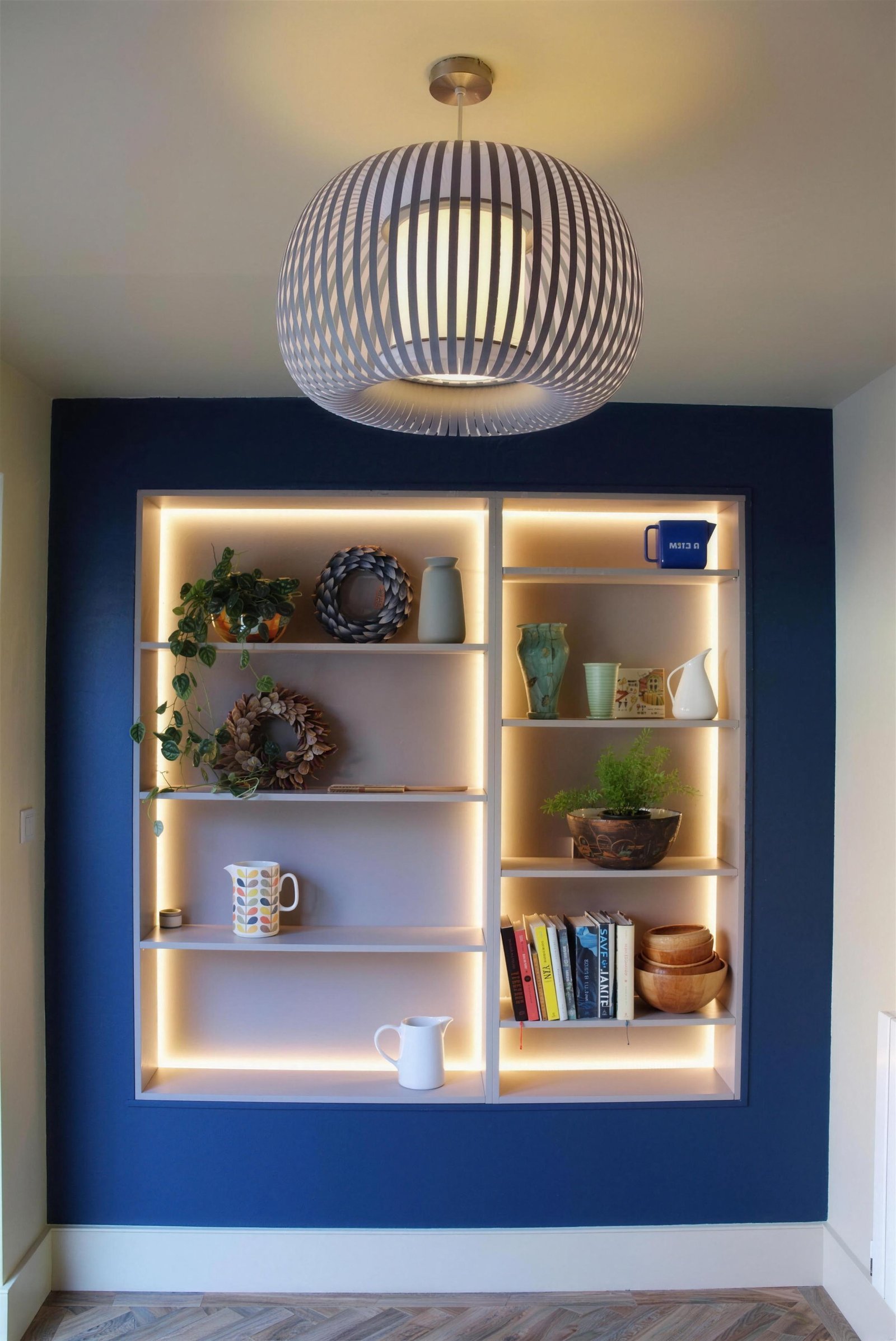 Bespoke alcove shelving with integrated lighting on a navy wall