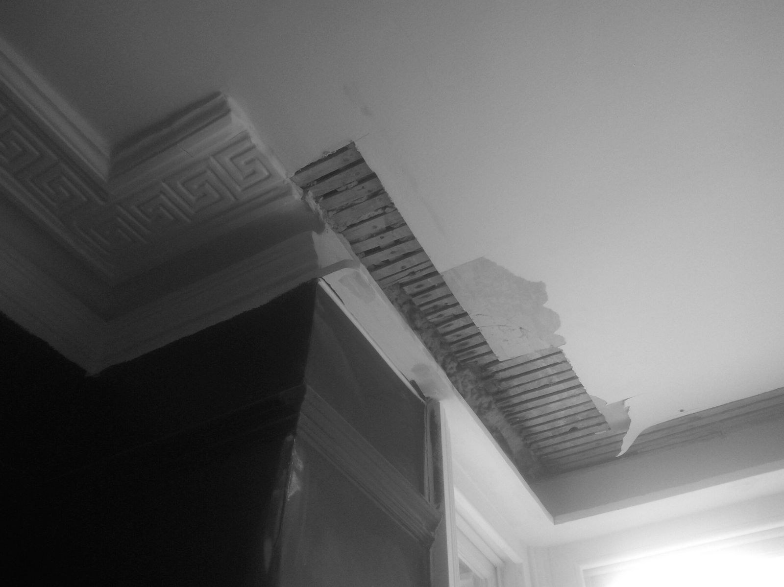 Greek key cornice with a damaged section stripped back to the laths