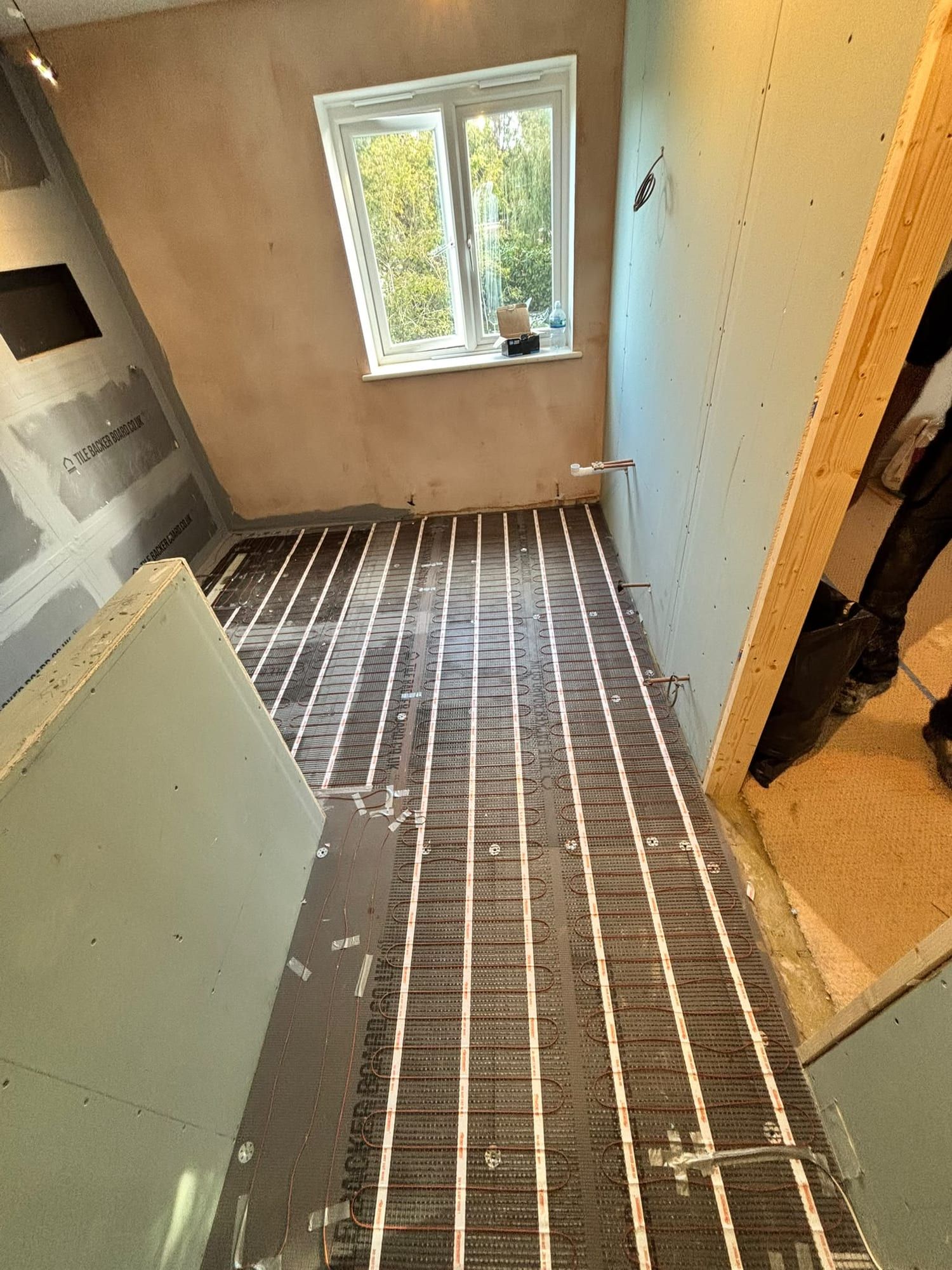 Electric underfloor heating mats laid across a floor before tiling, seen from the doorway